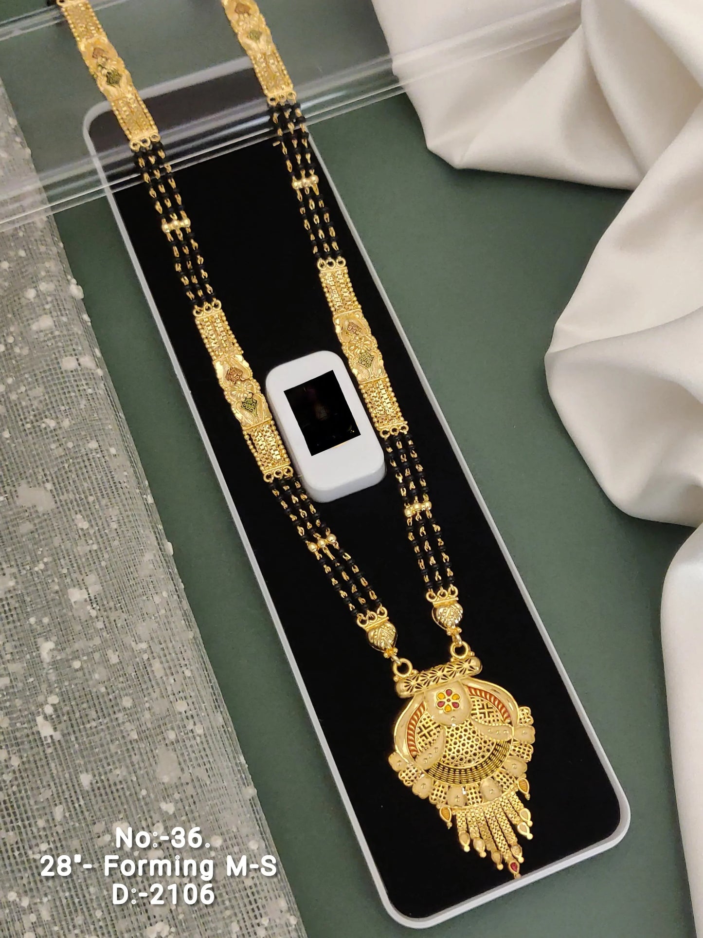 Traditional gold mangalsutra necklace with black beads displayed on a black velvet tray