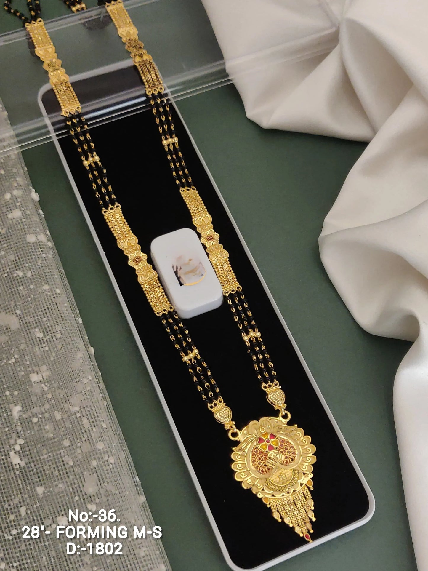 Traditional Indian gold and black beaded mangalsutra necklace with intricate floral pendant in black velvet box